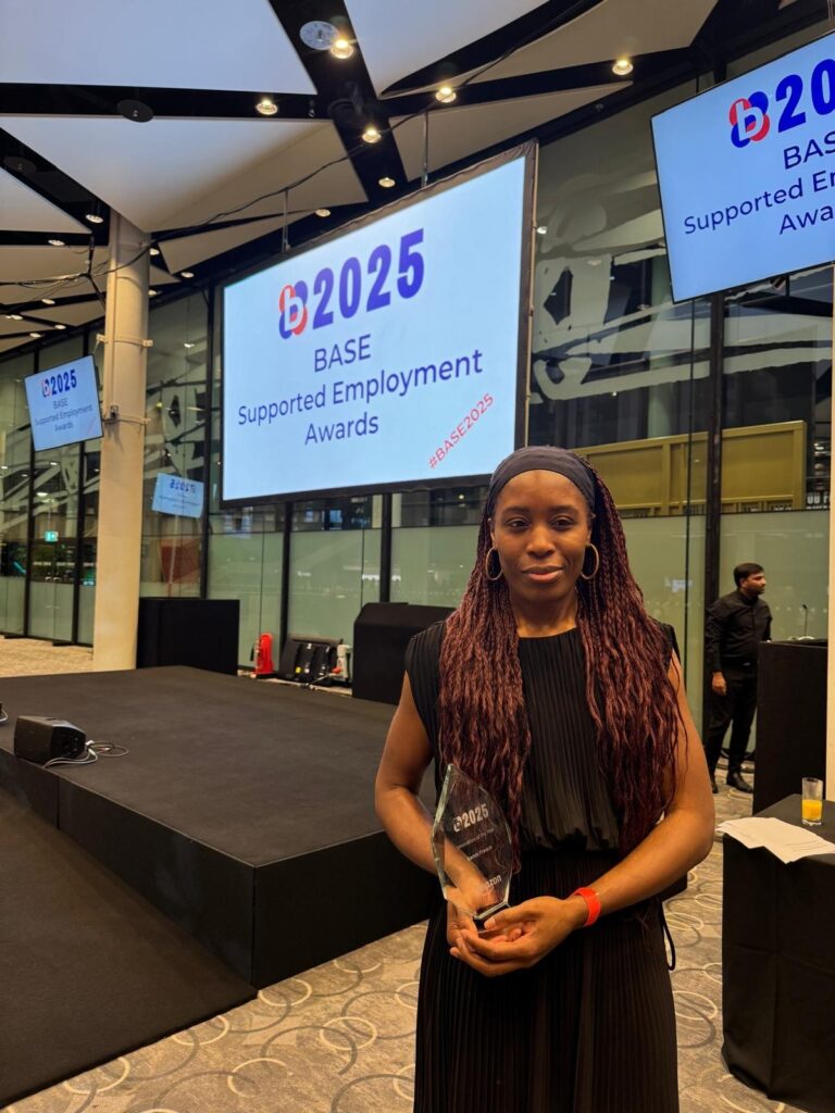 Bambi French, Team Leader for DurhamEnable, proudly holds her award below a sign reading 'BASE Supported Employment Awards'.